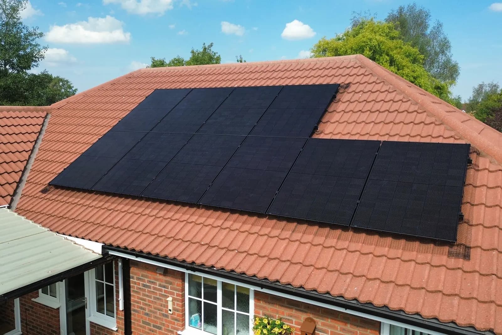 A black solar array fitted around the hip of a terracotta tiled bungalow