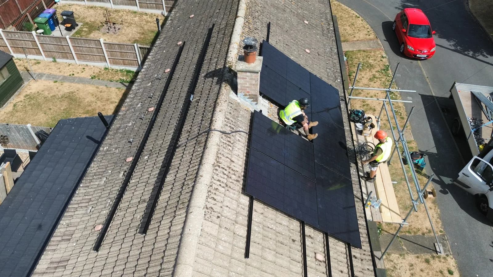 Installers fitting solar panels on a scaffolded roof