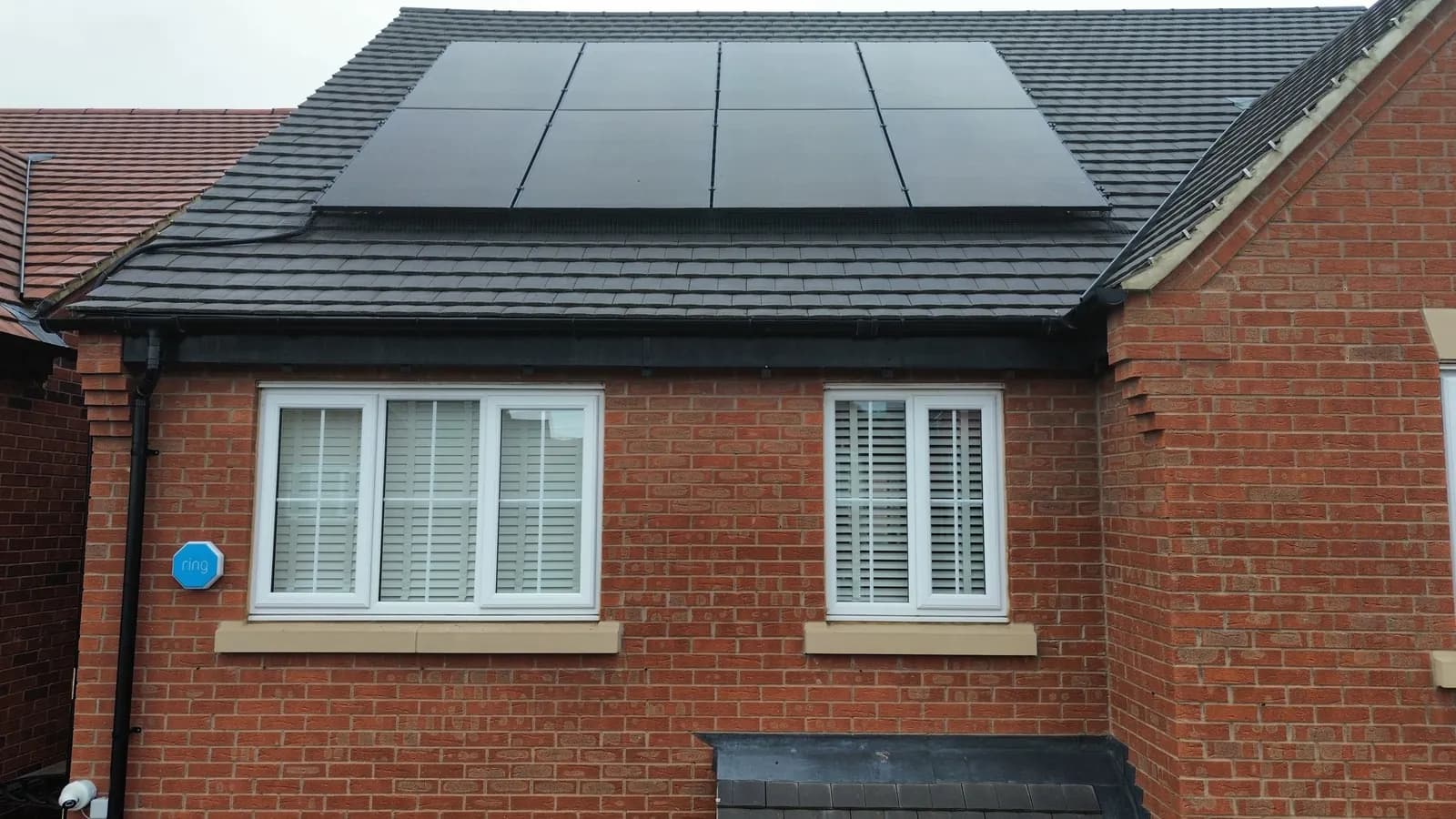 Black solar panels fitted across a pitched residential roof